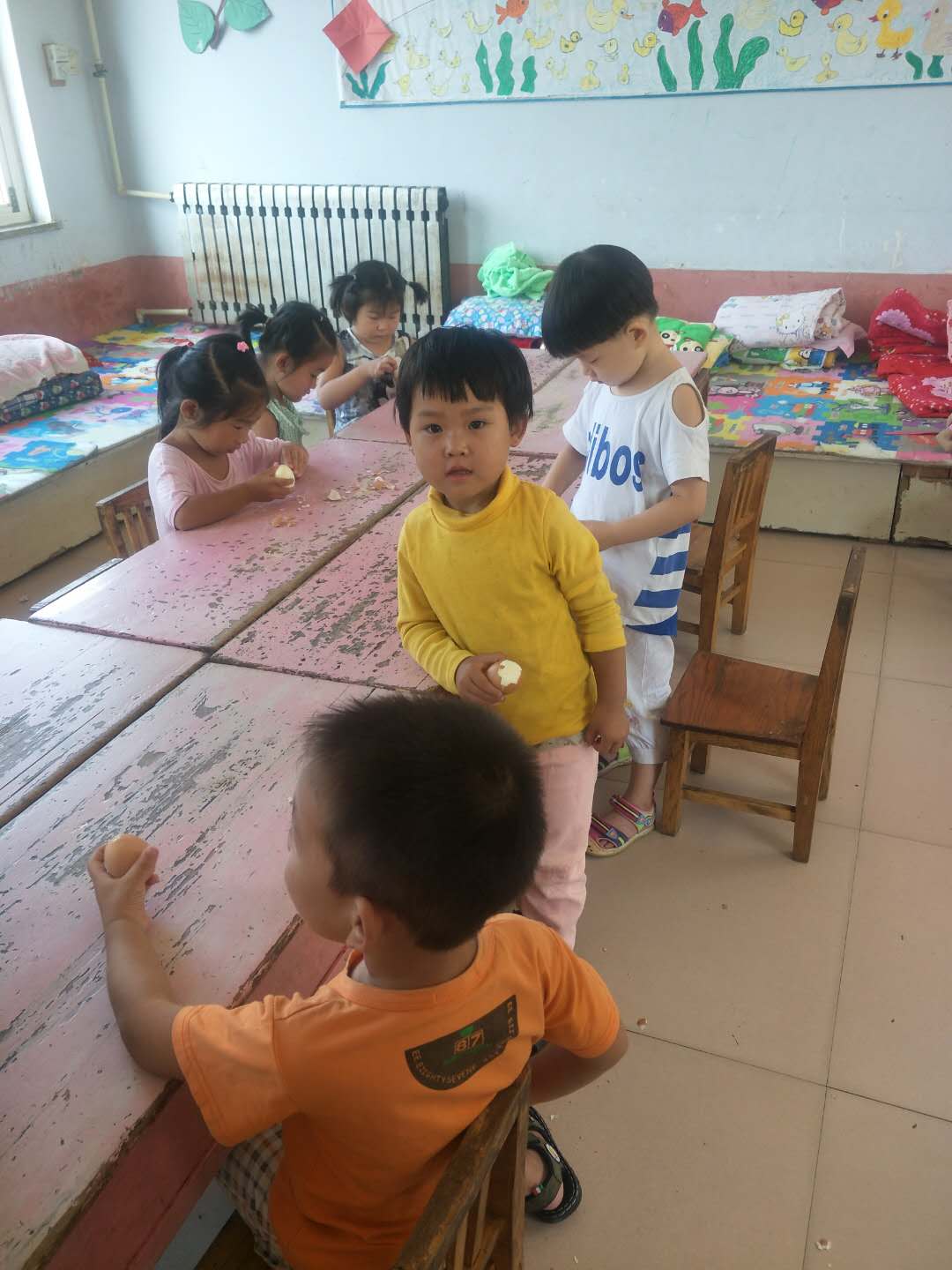在幼儿园，与小朋友在一起的妮妮（图中穿黄衣服者）